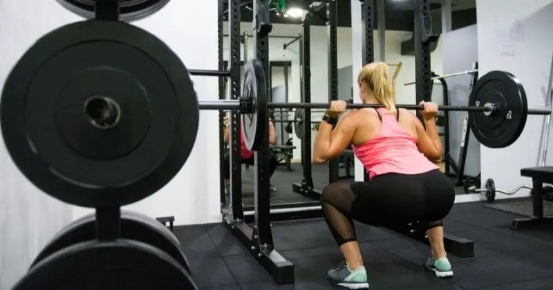 Best Folding Squat Rack - woman doing squats with a barbell