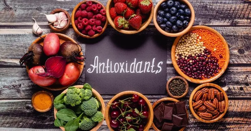 What are Antioxidants – Antioxidants written on a chalkboard, surrounded by fruits and vegetables.