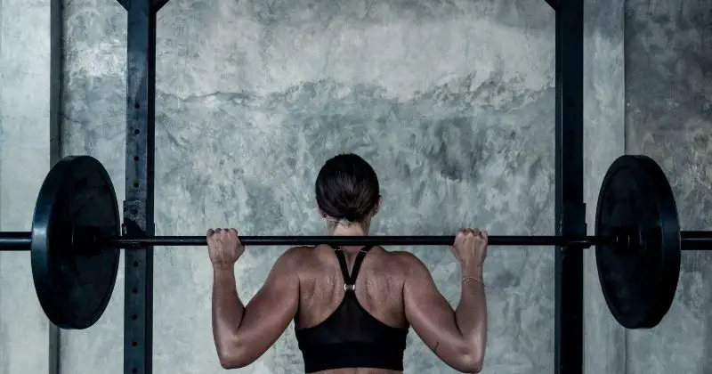 PRx Performance Fold-In ONE Squat Rack - Woman with a barbell and weights on her shoulders